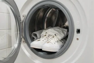 Basket Converse blanches placées dans un tambour de machine à laver avec des vêtements clairs, illustrant le lavage en machine sécurisé des sneakers