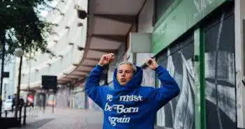 man in blue hoodie standing near green and white building during daytime
