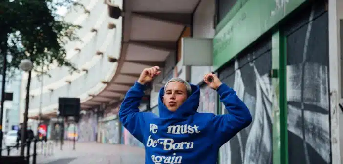 man in blue hoodie standing near green and white building during daytime