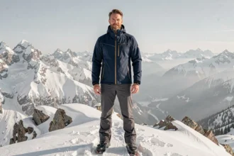 Homme en veste de ski haut de gamme bleu marine sur une crête enneigée avec panorama alpin