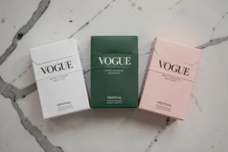 Trois paquets de cigarettes Vogue en différentes couleurs alignés sur du marbre blanc pour illustrer les variantes de la gamme